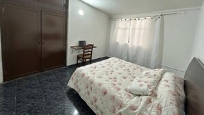 A bedroom with a bed, a desk, and a wardrobe.