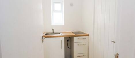 Una pequeña cocina americana con un lavabo, encimera de madera y dos cajones.