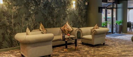 A lobby with a sofa set, a coffee table, and a floral wall mural.