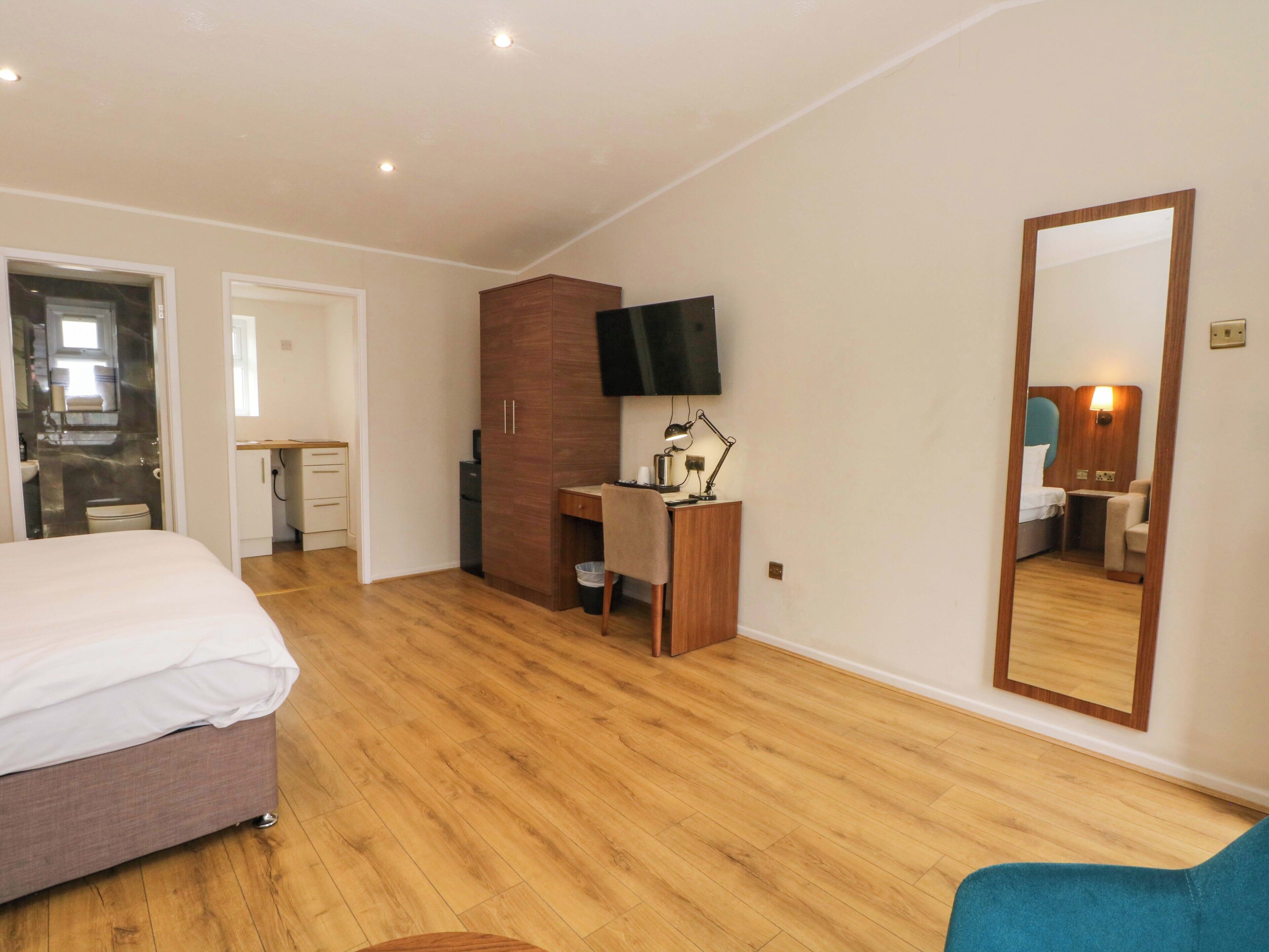 Une chambre à coucher avec un lit, un bureau, une chaise, une télévision et un miroir.