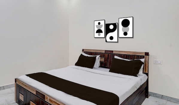 A bed with a wooden headboard, white bedding, and two black pillows.