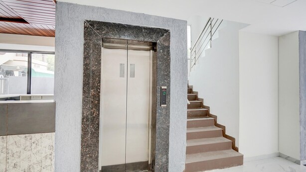 Een moderne lift met een digitaal scherm, een trap met een marmeren blad en een strak, minimalistisch interieur.