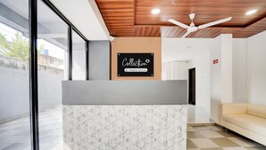 Een receptiebalie met een 'Collection' bord, een plafondventilator en een geruit vloertje.
