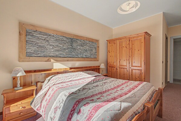 A bedroom with a bed, a nightstand, a wooden wardrobe, and a wall-mounted artwork. - 'Room 1' with Mountain View, Shared Terrace in Bionaz (Dzovennoz)