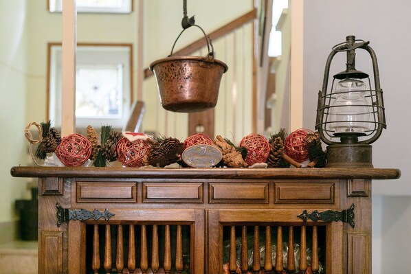 A wooden cabinet with decorative items including pine cones, a metal lantern, and a hanging copper pot. - 'Room 1' with Mountain View, Shared Terrace in Bionaz (Dzovennoz)