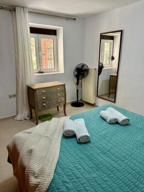 A bedroom with a bed, a dresser, a fan, a window, and a mirror. - Casa Joanna Old town Rethymno (Rethimno)