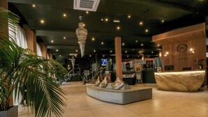 A lobby with a reception desk, a chandelier, a staircase, and a seating area. - Otter Lodge (Chorley)
