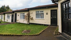 A row of single-story houses with a paved driveway and a grassy lawn. - Otter Lodge (Chorley)