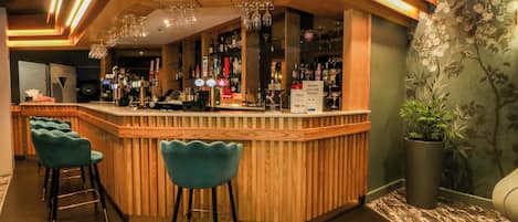 A bar area with wooden bar counter, bar stools, and a potted plant.