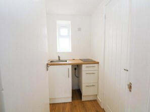 A small kitchenette with a sink, wooden countertop, and two drawers. - Hedgehog Lodge (Chorley)