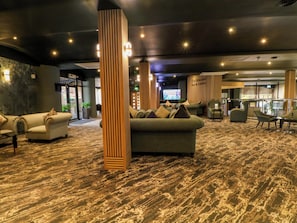 Una hall con divani, un pilastro in legno e un'area bar.