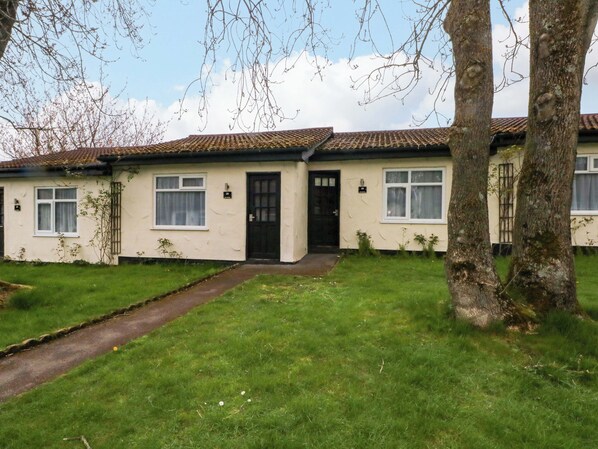A two-story house with a tiled roof, a front door, and a small front yard with grass and a pathway. - Hedgehog Lodge (Chorley)