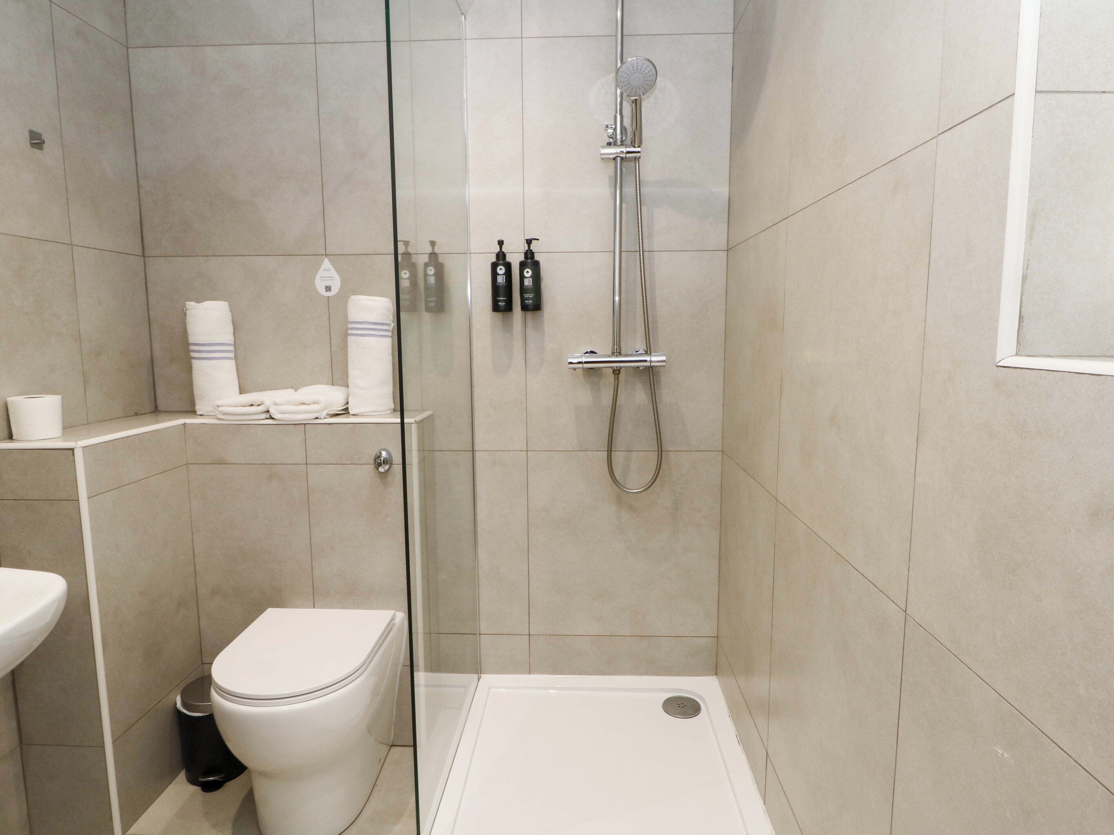 A modern bathroom with a glass-enclosed shower, a toilet, and a sink.