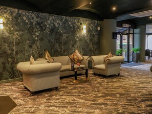 A lobby with a sofa set, a coffee table, and a floral wall mural. - Raven Lodge (Chorley)