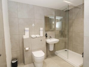 A modern bathroom with a toilet, sink, and glass-enclosed shower. - Raven Lodge (Chorley)