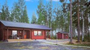 En træhytte med veranda, en mindre tilbygning og en grusvej.