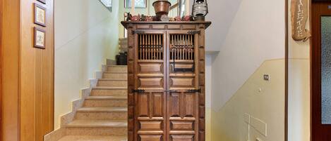Eine Holztreppe mit einem dekorativen Schrank am Obergeschoss.