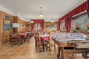 A restaurant with wooden paneling, red curtains, and a variety of dishes displayed on the counter. - 'Room 8' with Mountain View, Shared Terrace in Bionaz (Dzovennoz)