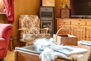 A cozy living room with a floral armchair, a wooden cabinet, and a television. - "Room 9" with Mountain View, Shared Terrace in Bionaz (Dzovennoz)