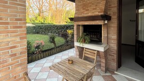 Eine Terrasse im Freien mit Kamin aus Ziegelsteinen, einem Holztisch und Stühlen.