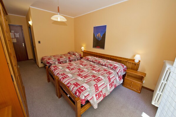 A bedroom with two beds, wooden headboards, bedside tables with lamps, a poster on the wall, and a radiator. - "Room 10" with Mountain View, Shared Terrace in Bionaz (Dzovennoz)