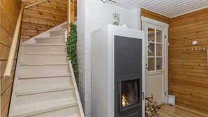 Uma escadaria com corrimão branco, uma lareira com fogo visível e uma porta com painéis de vidro.
