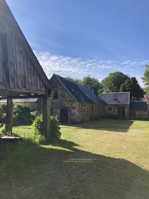 A rustic stone building with a sloped roof, surrounded by a grassy area and trees. - Beautiful country house 5 minutes from the beaches of Perros-Guirrec, ideal for families (Lannion)