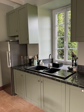 A kitchen with two sinks, a window, and a view of greenery outside. - Beautiful country house 5 minutes from the beaches of Perros-Guirrec, ideal for families (Lannion)
