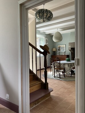 A staircase leading to a dining area with a table, chairs, and a hanging light fixture. - Beautiful country house 5 minutes from the beaches of Perros-Guirrec, ideal for families (Lannion)