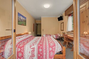 A hotel room with a large bed, a desk, a chair, and a television. - Triple Room 11 with Mountain View and Shared Terrace in Bionaz (Dzovennoz)