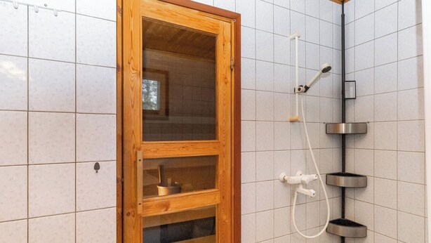Een douche met een houten kast, betegelde wanden en een metalen douchekop.