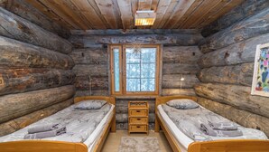 Eine Hütte mit zwei Holzbetten, einem Fenster, einem Teppich und einem Bild an der Wand.
