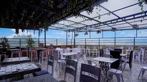 An outdoor cafe with tables and chairs, a tiled floor, and hanging plants. - Super Deluxe Room Hotel Mayvilas (Dehradun)