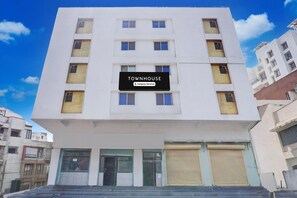 A multi-story building with a sign reading 'TOWNHOUSE' and a company-serviced logo. - Super Deluxe Room White Castle (Pune)