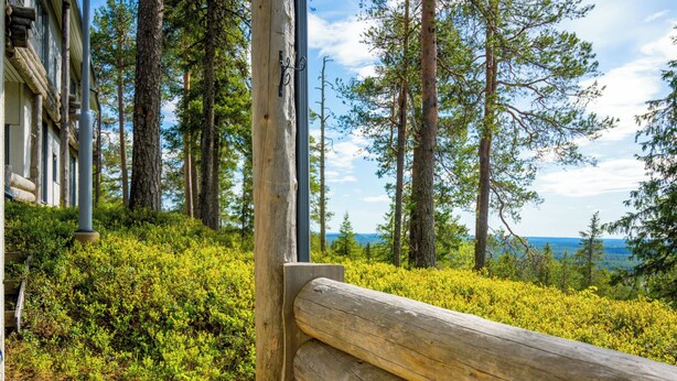 A wooden bench, a building with a log cabin exterior, and a forested area with a view of the water. - Rukatunturintie 8 g2 by Interhome (Kuusamo)