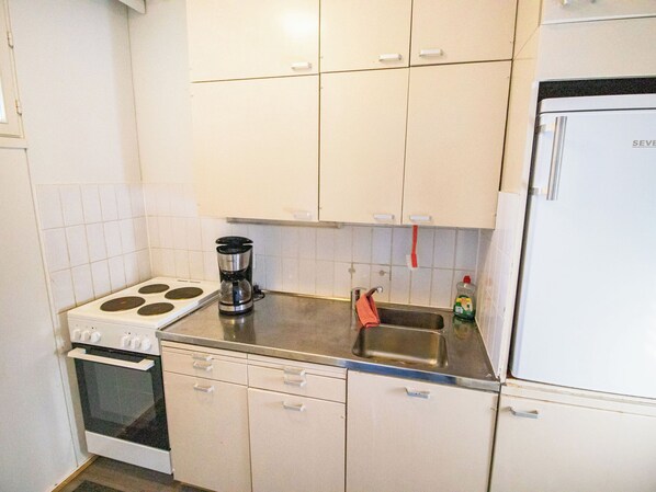 A kitchen with a stove, oven, coffee maker, sink, and a refrigerator.
