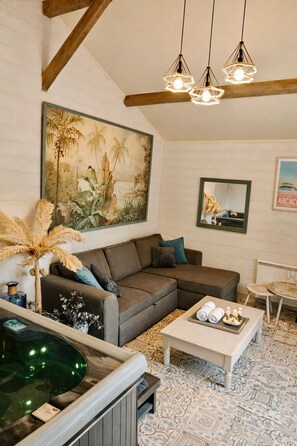 A living room with a sectional sofa, a small table, a hot tub, and a large painting. - La Dolce Quercy, charming gîte with swimming pool & SPA (Espère)