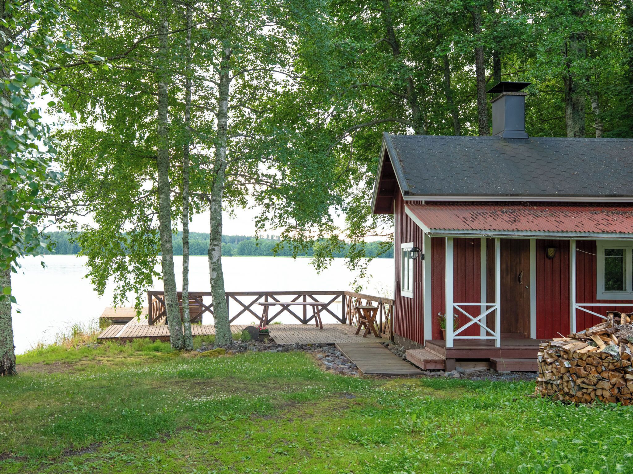 Una cabaña con un muelle, rodeada de árboles y un lago.