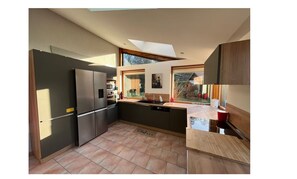A modern kitchen with a large window, built-in appliances, and a skylight. - Charming family home in Normandy (Chamblac)