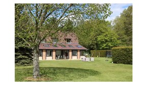 Ein Haus mit Backsteinfassade, großen Fenstern und einem Rasen.