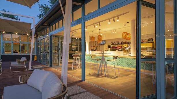 Ein moderner Außenbereich mit Bar, Holzterrasse, Sitzgelegenheiten und einer Bartheke.
