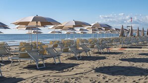 Ein Strand mit Liegestühlen und Sonnenschirmen.