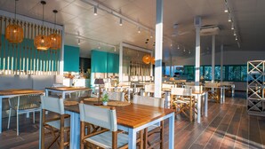 Ein geräumiges Restaurant mit hohen Decken, modernen Pendelleuchten und einer Mischung aus Holz- und weißen Möbeln.