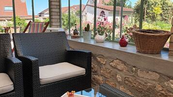 Une chaise en osier avec un coussin, un panier en osier et des objets décoratifs placés sur une étagère.