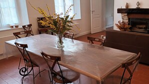 En matplats med ett bord, stolar, en vas med blommor, en öppen spis och en soffa.