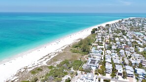 An aerial view of a coastal residential area with beachfront properties, dense vegetation, and a clear view of the ocean. - Waves Edge - Beachfront! (Anna Maria)