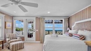 Ein Schlafzimmer mit Bett, Stuhl, Deckenventilator und Blick ins Freie.