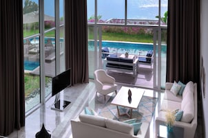 A modern living room with a large window overlooking a pool and garden.
