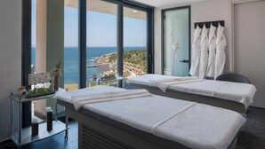 A spa room with two beds, a small table with a vase and teapot, and a view of the sea. - Vitalica Wellness Bodrum (Bogazıcı)