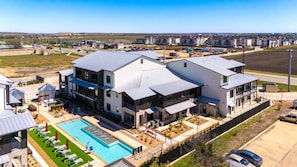 A modern multi-story residential building with a swimming pool and outdoor seating area. - Unwind in Style: Luxe Condo Getaway! (New Braunfels)